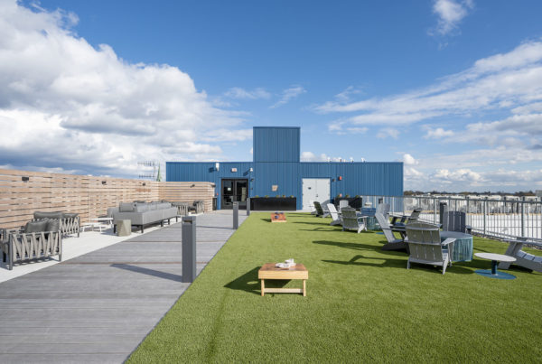 Roofdeck view looking east showing cornhole boards and seating on the turf strip roof deck